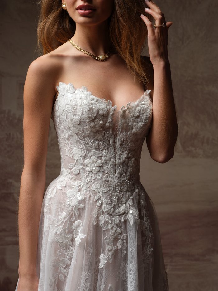 Close-up of a bride wearing a pearl choker, showing the sweetheart neckline and floral lace bodice of the Hadley A-line wedding dress by Maggie Sottero.