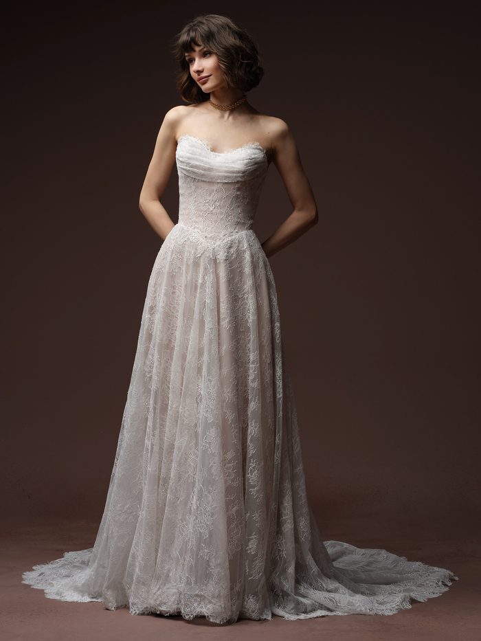 Bride wearing the Maelle A-line wedding dress by Maggie Sottero, featuring a strapless lace bodice with a ruched draped neckline and a full lace A-line skirt with a train.