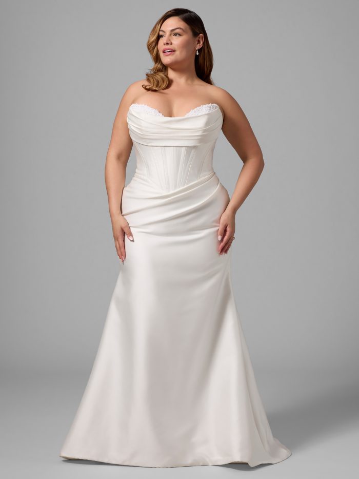 Plus-size model wearing the Melissa fit-and-flare wedding dress by Maggie Sottero, featuring a strapless sweetheart neckline with beaded edge, corset bodice, and satin skirt with side draping.