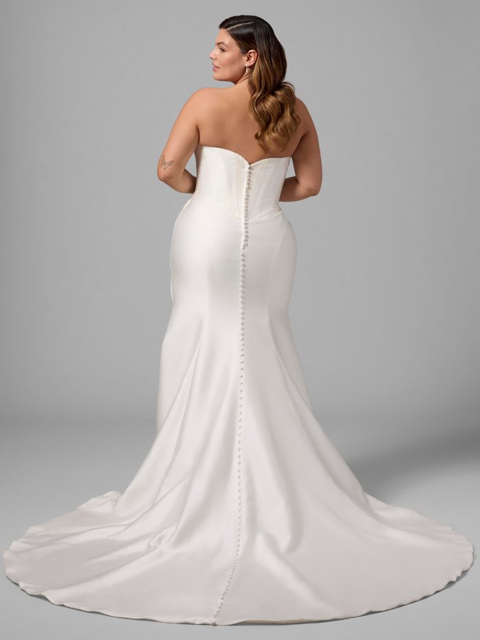 Back view of the Melissa fit-and-flare wedding dress by Maggie Sottero on a plus-size model, showing the strapless corset bodice with covered button closure down the train.