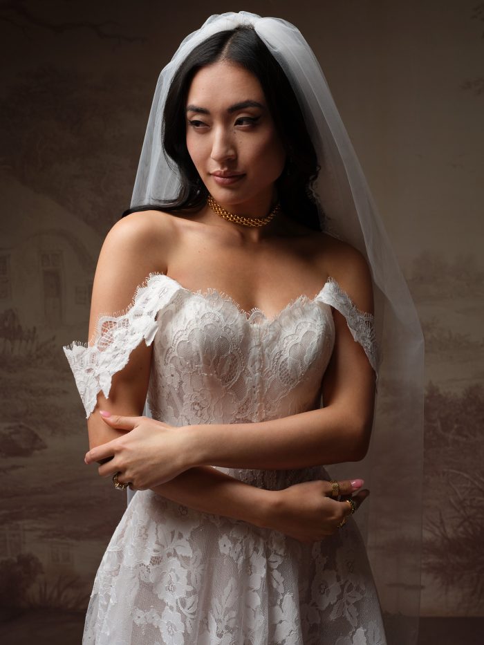 Close-up of the Mischa wedding dress by Maggie Sottero, showing the lace bodice and off-the-shoulder scalloped sleeve detail.
