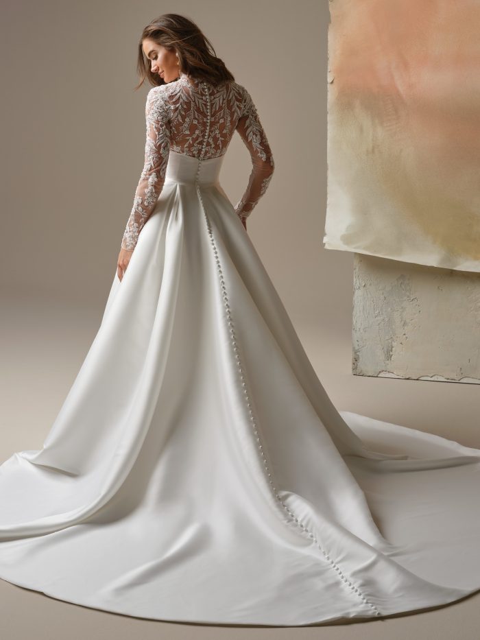 Back view of the Trinity A-line wedding dress by Maggie Sottero, showing the illusion lace long-sleeve bodice with a row of covered buttons down the back and a sweeping satin train.