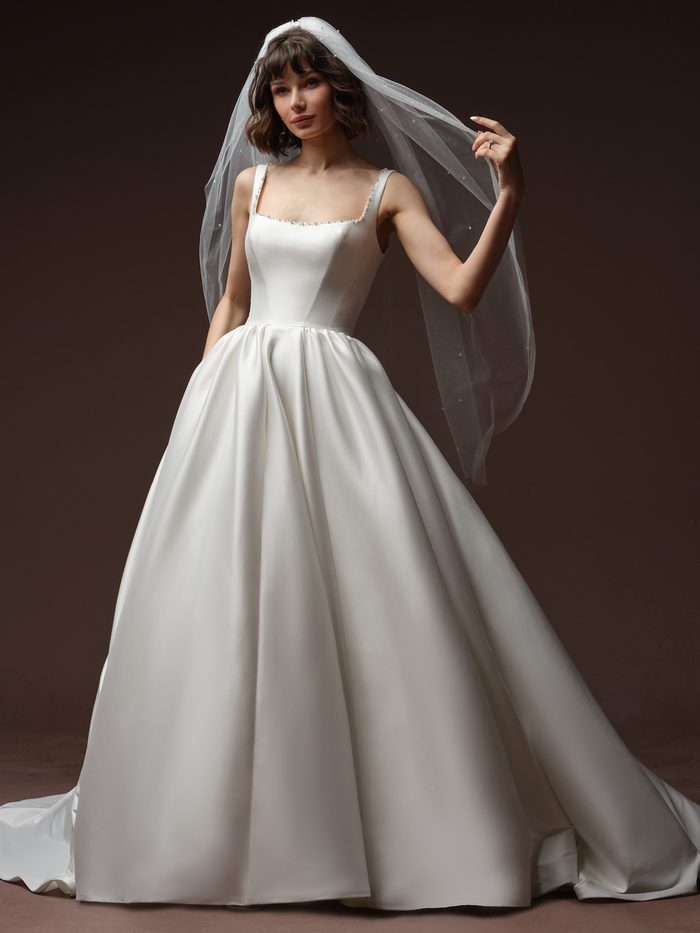 Front view of a model wearing the Astoria veil from the Essentials Edit by Maggie Sottero, a pearl-scattered tulle veil with a beaded edge, paired with the Zurielle A-line Wedding Dress by Maggie Sottero.