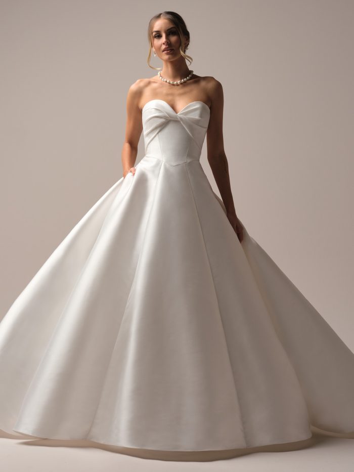 Front view of the Brooke ballgown wedding dress by Rebecca Ingram, featuring a strapless sweetheart neckline with folded satin bodice detail and a voluminous satin ballgown skirt.