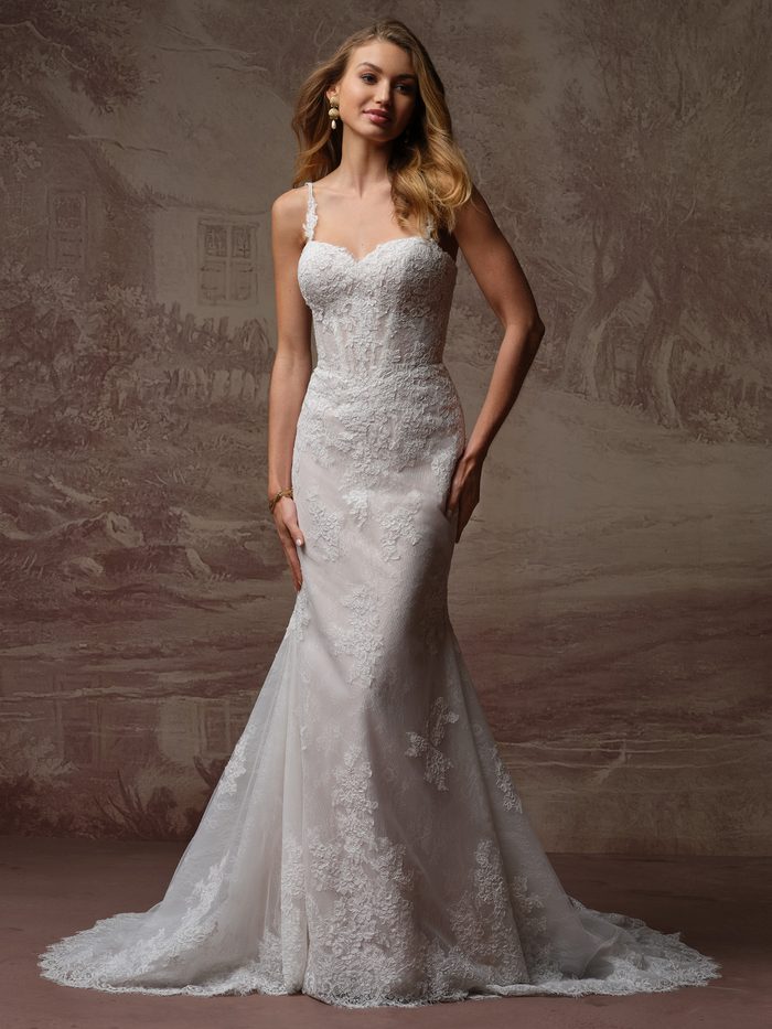 Bride wearing the Esmeralda Lane fit-and-flare wedding dress by Rebecca Ingram, featuring a lace bodice with thin straps, a sweetheart neckline, and a fitted lace skirt with a flared train.