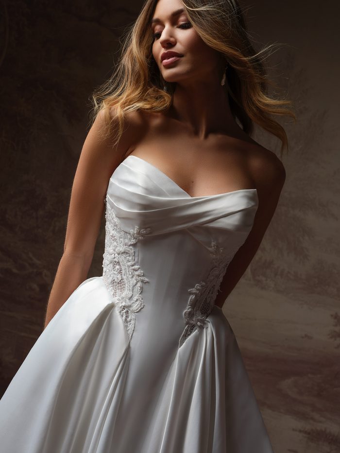 Close-up of the Gigi ballgown wedding dress by Rebecca Ingram, showing the draped satin bodice with beaded lace side panels.