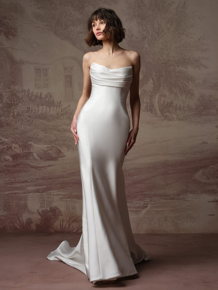 Kayla by Rebecca Ingram fit-and-flare wedding dress with a draped strapless neckline, sculpted satin bodice, and elegant minimalist bridal silhouette.