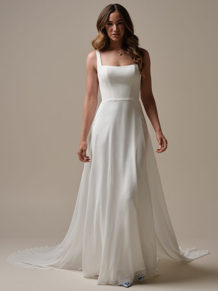Bride wearing the chiffon Olivianna A-line wedding dress by Rebecca Ingram, featuring a minimalist square neckline bodice and a flowing skirt with a train.