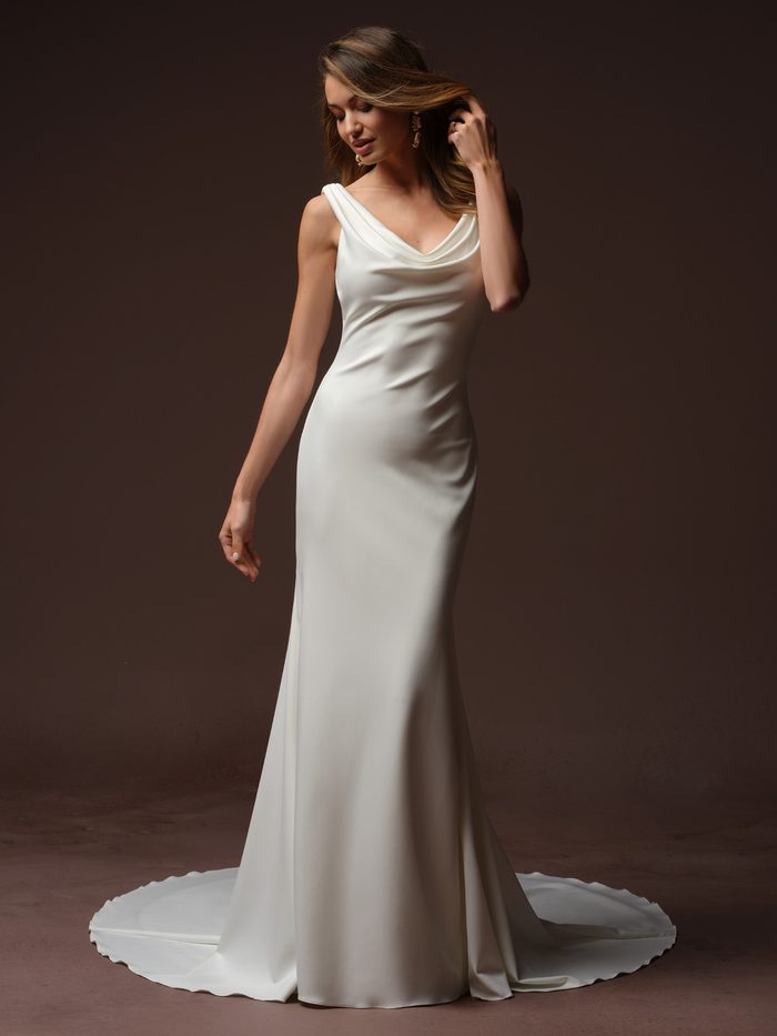 Bride wearing the Tiana sheath wedding dress by Rebecca Ingram, featuring a draped cowl neckline with wide straps and a fitted satin sheath skirt with a train.