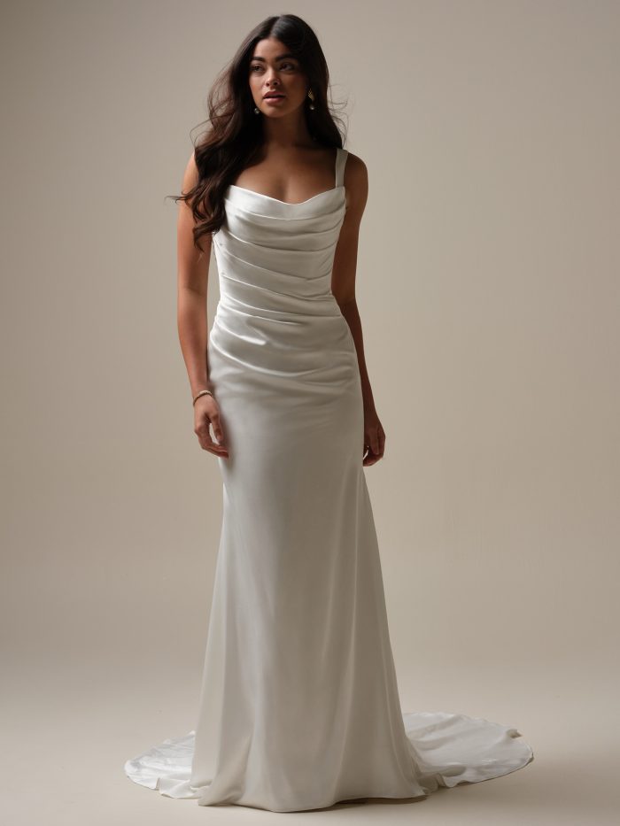 Tommie by Rebecca Ingram sheath wedding dress featuring a draped cowl neckline, minimalist satin fabric, wide shoulder straps, fitted silhouette, and elegant sweep train.