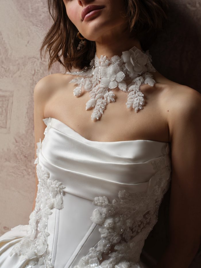 Close-up of the Burke Bridal Choker by Sottero and Midgley, showcasing dimensional floral appliqués, sequined leaf motifs, and delicate beaded accents, styled with the Burke Lane ballgown's draped satin neckline and textured floral embellishments.