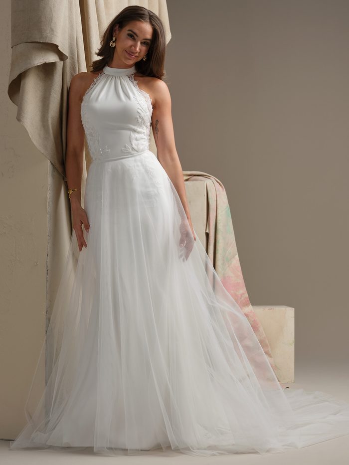 Model wearing Milos overskirt from Maggie Sottero Essentials Edit Collection with a halter-neck wedding dress featuring lace appliqués and a flowing tulle skirt.