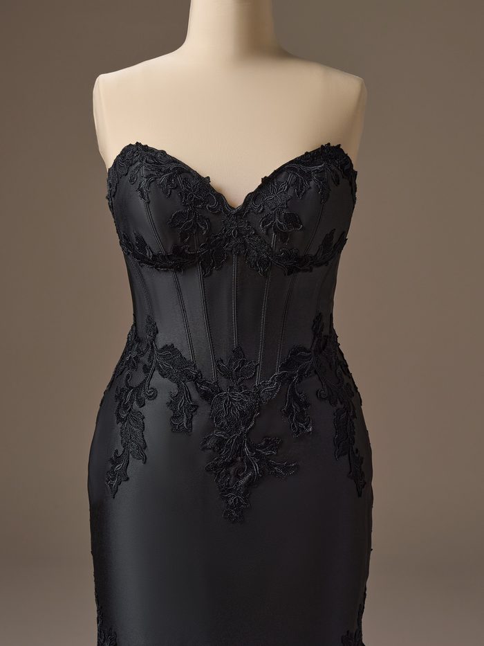 Close-up front view of the Maggie Sottero Serafina Lane A-Line wedding dress in black, featuring a strapless sweetheart neckline, structured corset-inspired bodice, and intricate floral lace appliqués cascading across the bodice and skirt.
