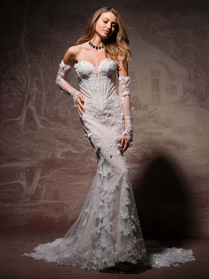 Stasia by Maggie Sottero fit-and-flare wedding dress with floral lace appliqués, sheer detached sleeves, and a fitted silhouette.